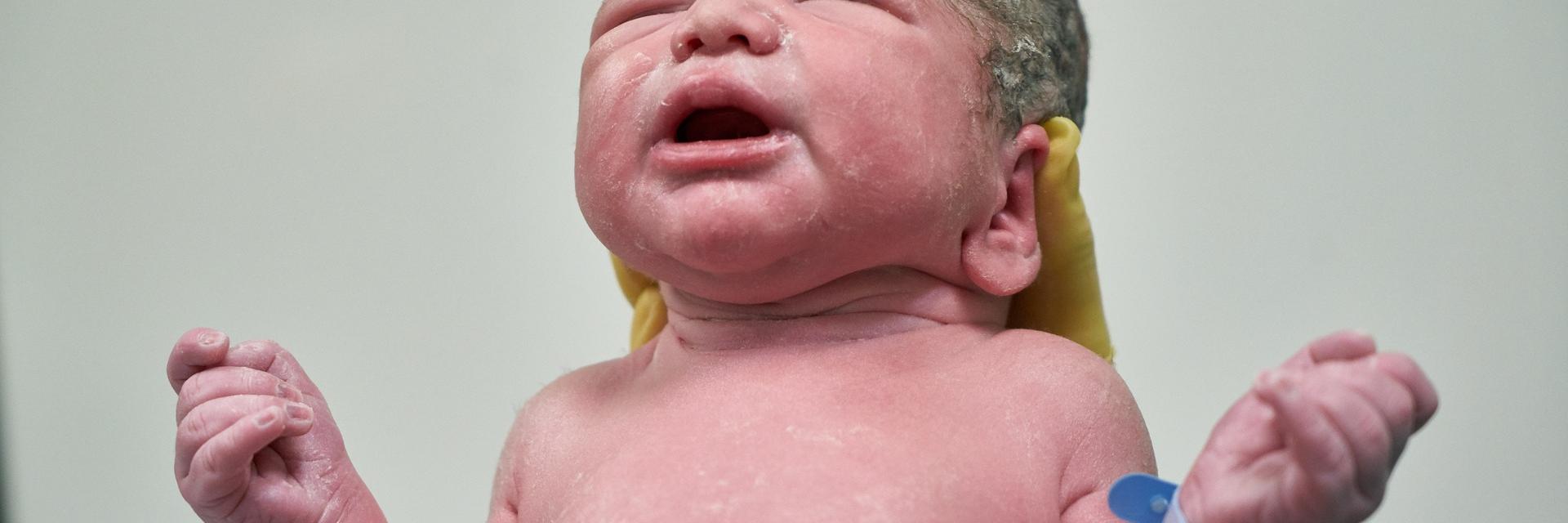Pasgeboren baby met gespreide armen.