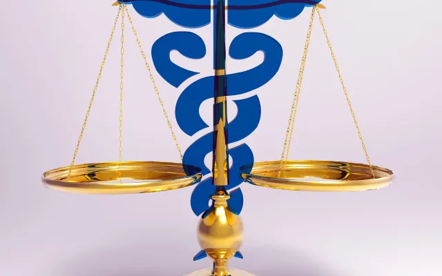Een weegschaal met het symbool van de caduceus erachter.