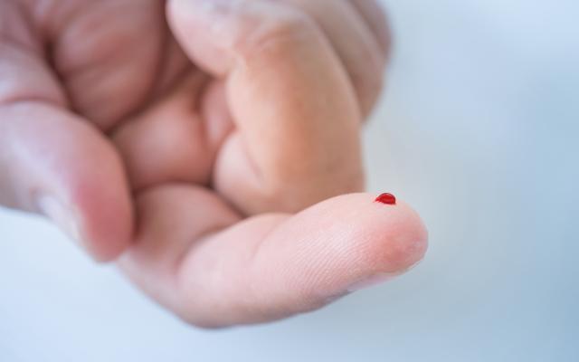 Een vinger met een druppel bloed.