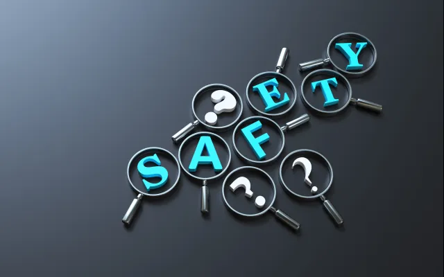 Het woord 'Safety' omringd door vraagtekens. Op elke letter en vraagteken ligt een vergrootglas.