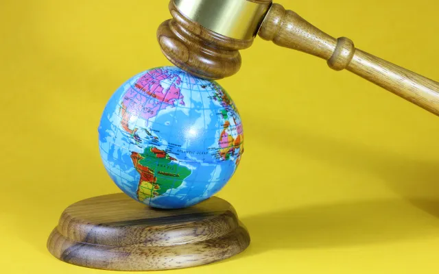 Een kleine globe onder een voorzittershamer.