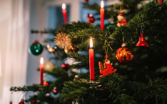 Een kerstboom versierd met kaarsen.