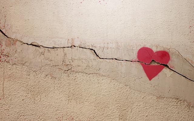 Een getekend hart op een muur of vloer. De ondergrond is gebarsten en de barst loopt door het hart heen.