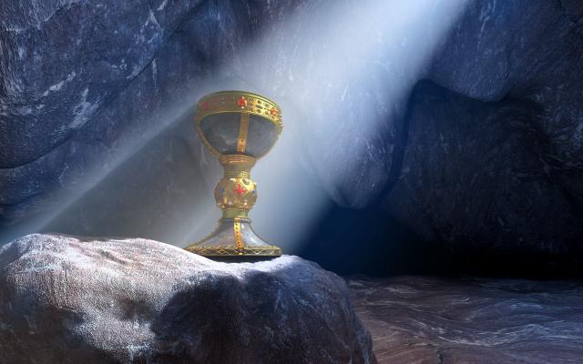 Beeld van een 'heilige graal': een gouden beker staat op een rots. Een lichtstraal valt over het voorwerp heen.