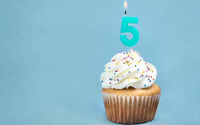 Een cupcake met een kaarsje in de vorm van het cijfer 5.