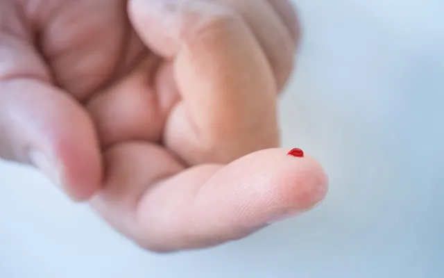 Een vinger met een druppel bloed.