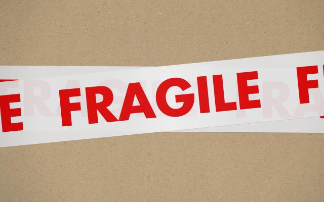 Close-up van een sticker met het woord 'FRAGILE' op een stuk karton.