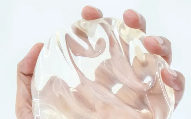 Een hand houdt een siliconen borstimplantaat vast.