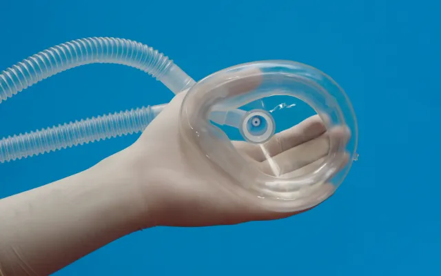 Een kinderhand houdt een zuurstofmasker vast.