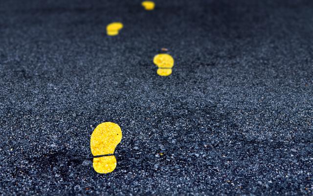 Gele voetstappen op asfalt