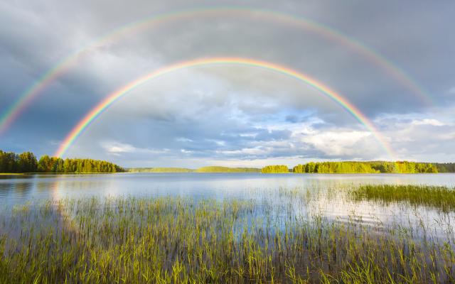 Een dubbele regenboog boven een meer.