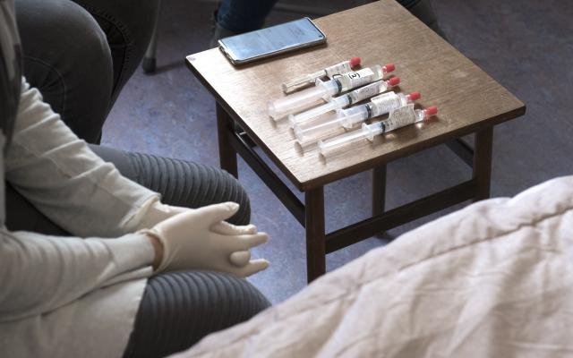 Op een klein tafeltje ligt een rij injectiespuiten.