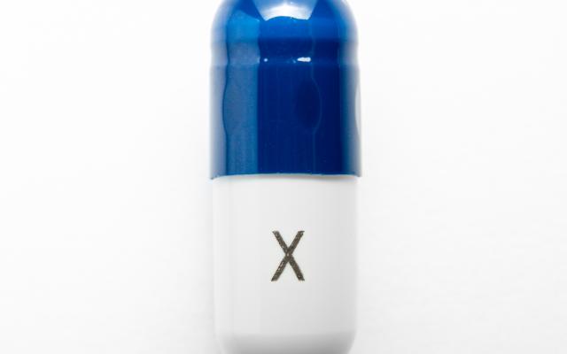 Blauwwitte capsule met een X op de onderkant geschreven.