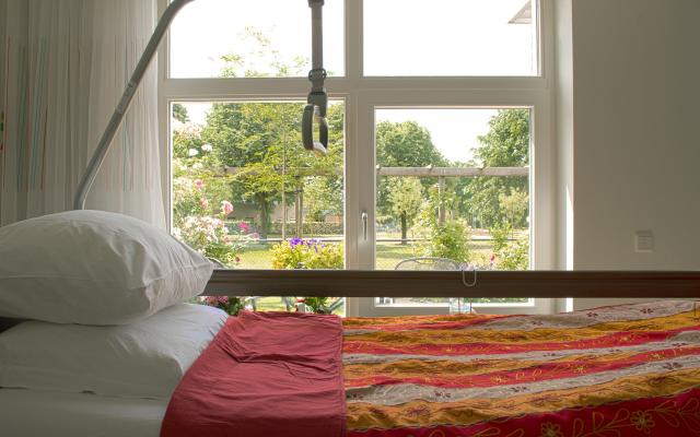 Een ziekenhuisbed naast een raam met uitzicht op een groene omgeving.