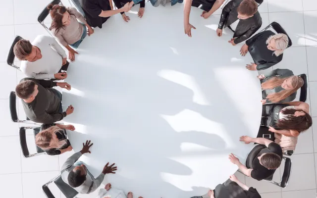 Een groep mensen zit aan een ronde tafel.