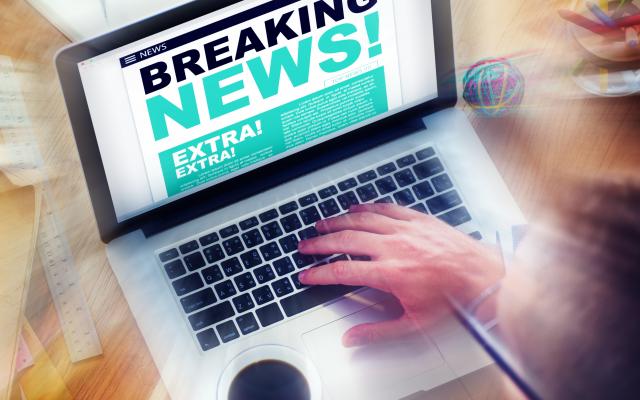 Op het scherm van een laptop staan de woorden 'breaking news'.