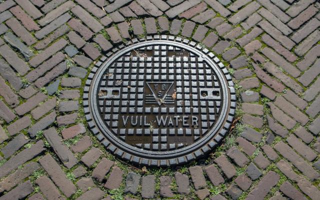 Putdeksel met de tekst 'vuil water'.