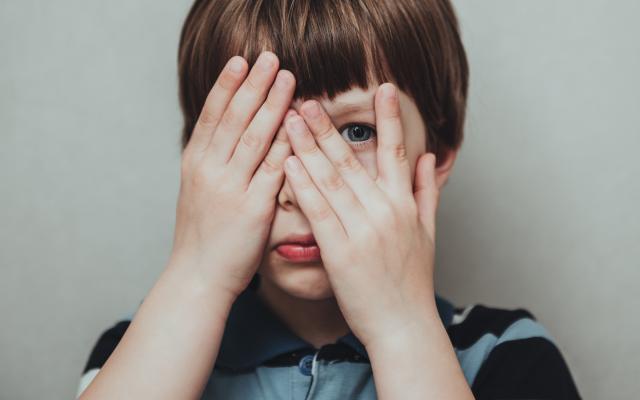 Jongen met handen voor zijn ogen