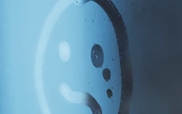 Een beslagen ruit met een ongelukkige smiley erop getekend