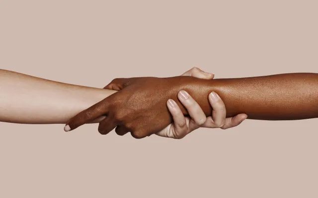 Een zwart en witte hand die elkaar vastpakken