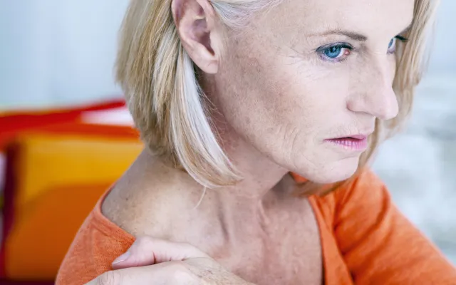 Vrouw die haar schouder vastpakt