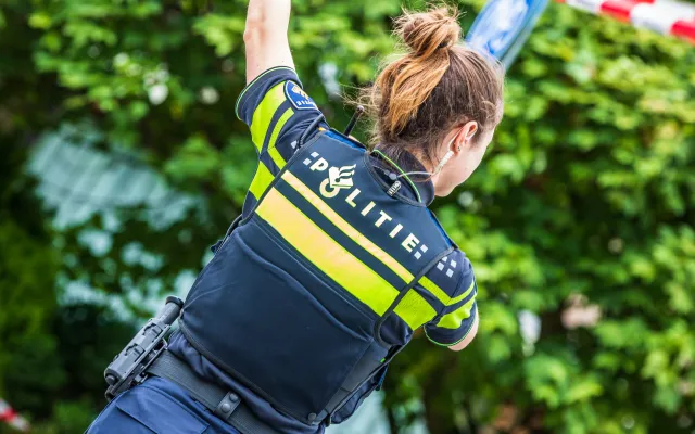 Een politieagent die cordon omhoog houdt