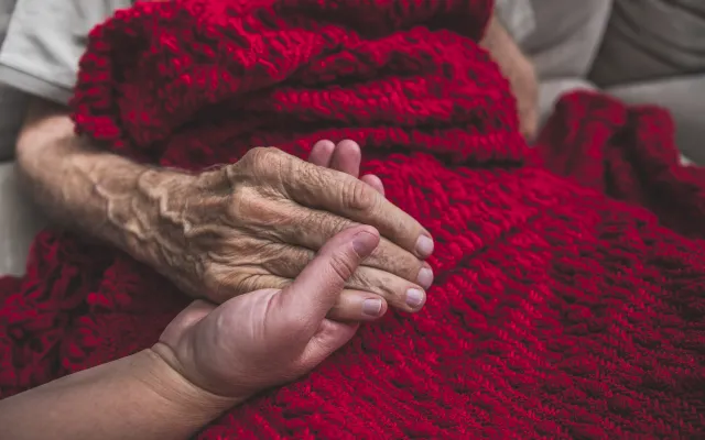 Een jonge hand die een oude hand vasthoudt