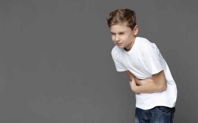 Jongen die zijn buik vasthoudt