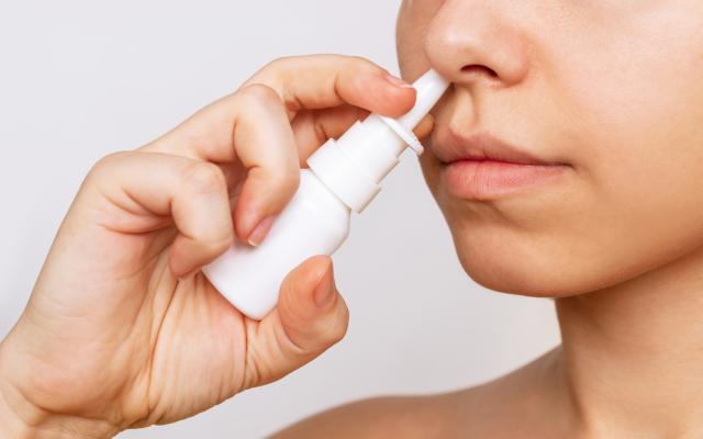 Een vrouw die neusspray in haar neus sprayt