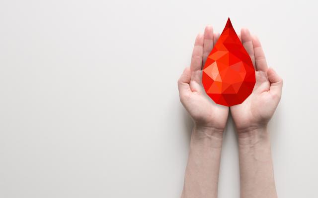 Een kristalvormige druppel bloed in twee handen