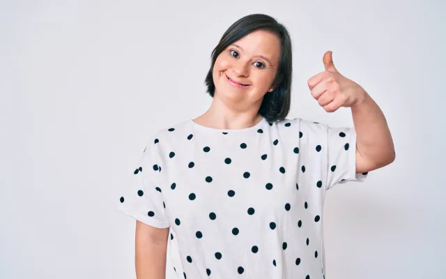 Vrouw met downsyndroom die duim omhoog houdt