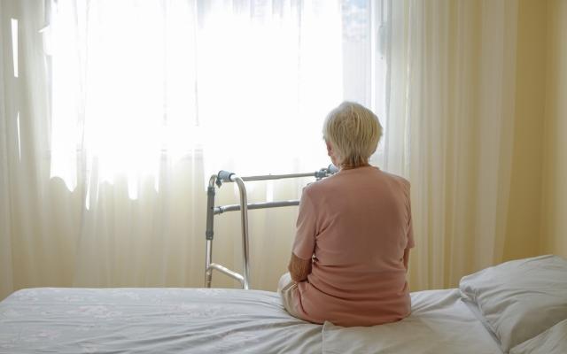 Vrouw die op een bed zit met een rollator voor zich