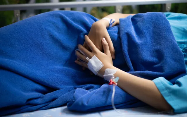 Beeld: justplay1412/Shutterstock Persoon ligt zijwaarts met beide handen voor de buik.