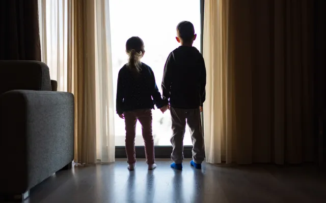 Beeld: SanyaSM/iStock.com Twee kinderen die voor een raam staan