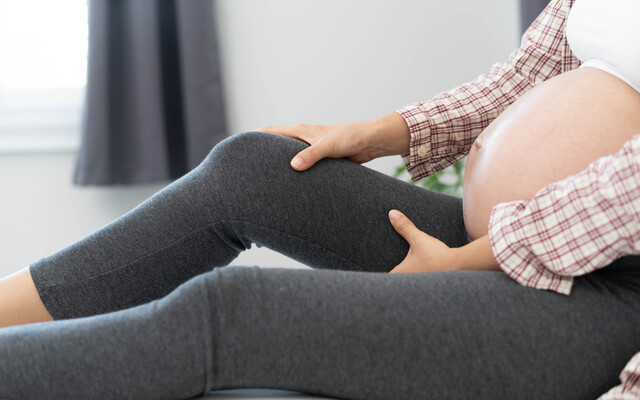 Zwangere vrouw die haar been vasthoudt