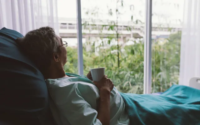 Iemand die vanuit een ziekenhuisbed naar buiten kijkt