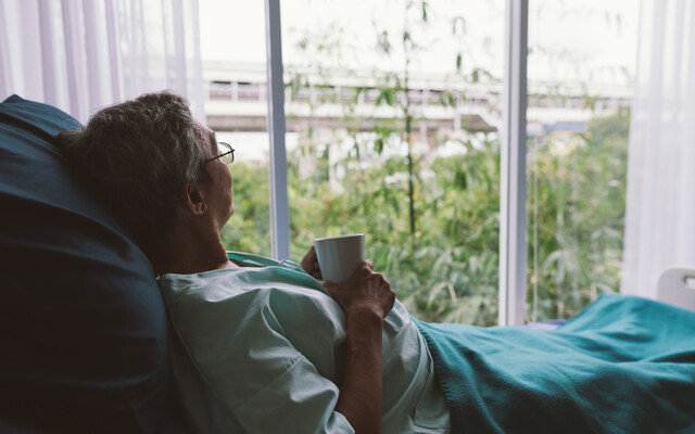 Iemand die vanuit een ziekenhuisbed naar buiten kijkt