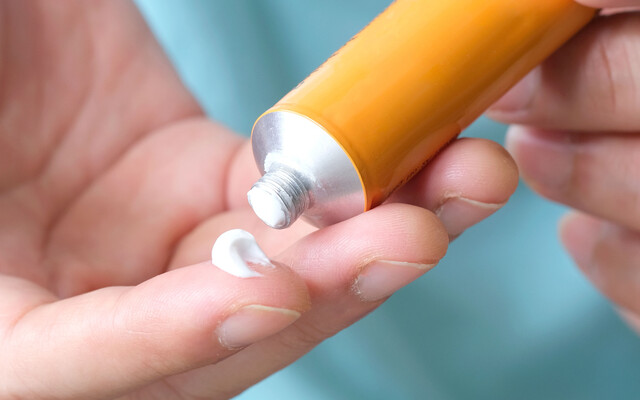 Hand met crème uit een tube