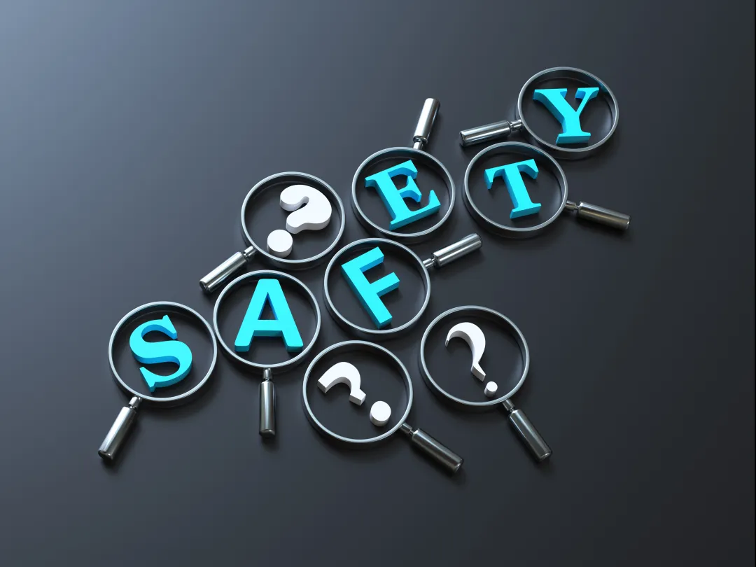 Het woord 'Safety' omringd door vraagtekens. Op elke letter en vraagteken ligt een vergrootglas.