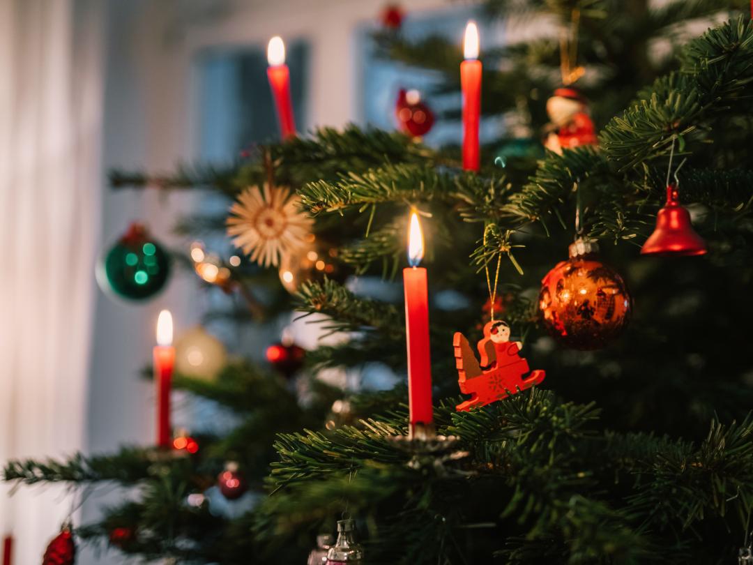 Een kerstboom versierd met kaarsen.
