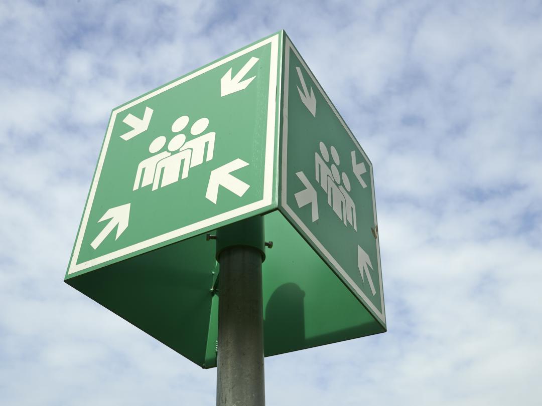 Een vierkant groen bord waarop vier personen zijn afgebeeld. Vanuit de vier hoeken wijzen pijlen naar de groep mensen.