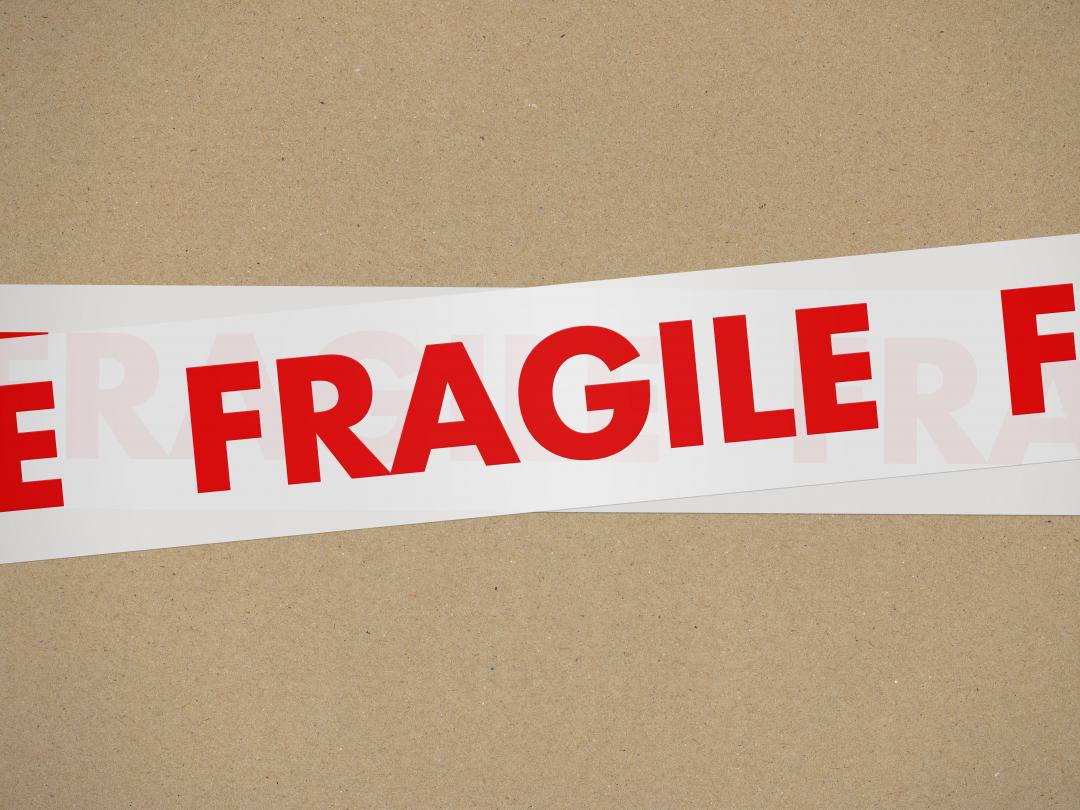 Close-up van een sticker met het woord 'FRAGILE' op een stuk karton.