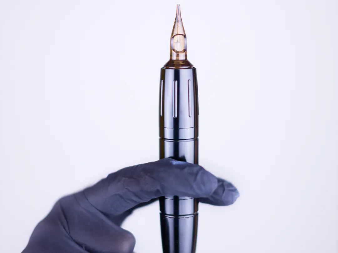 Een hand houdt een tattoomachine vast.