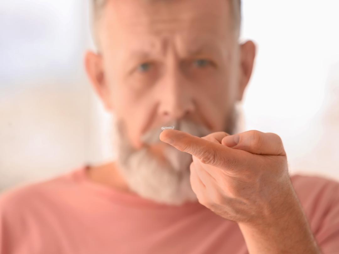 Een man houdt een lens op zijn vingertopje.