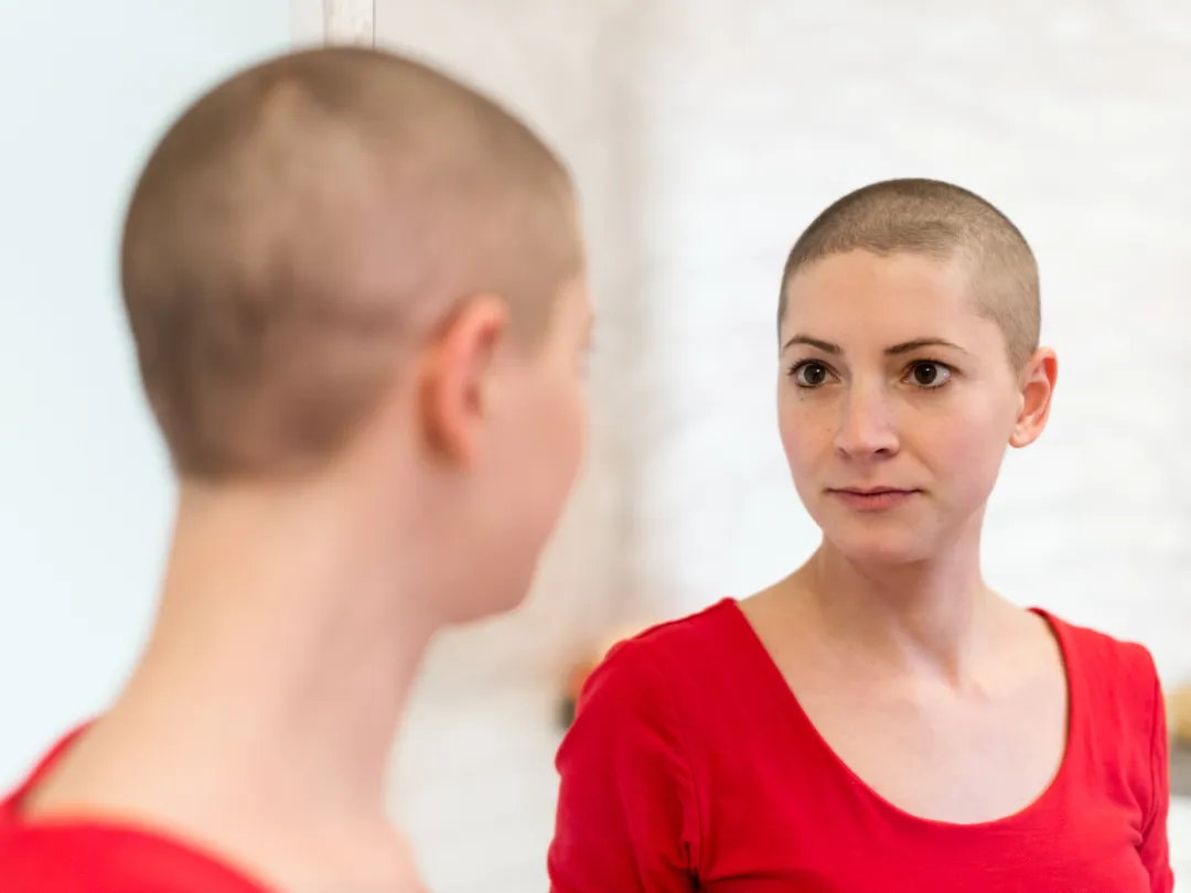 Dame met kortgeschoren haar die in de spiegel kijkt