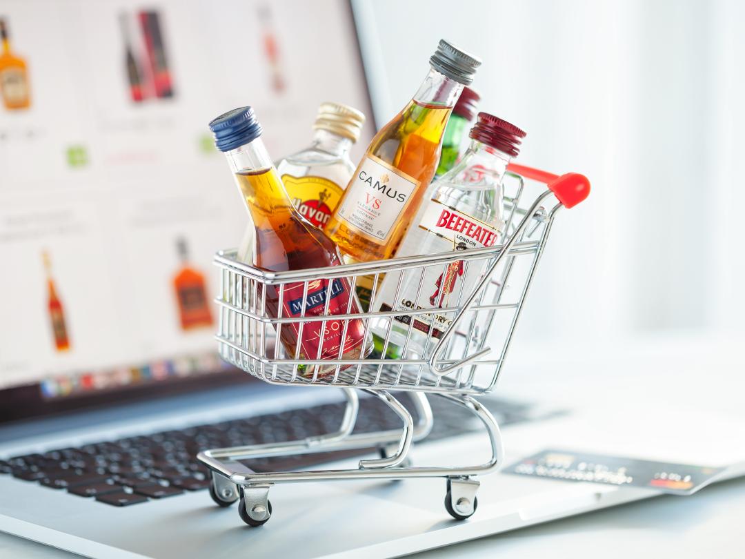 Een mini winkelkarretje vol met drank op een laptop