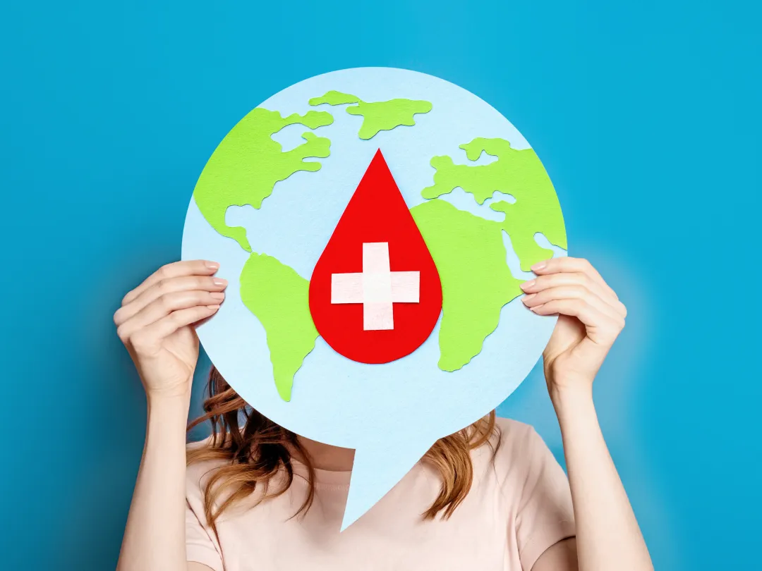 Een vrouw met een tekstballon daarop de wereld en een rood kruis in de vorm van een druppel