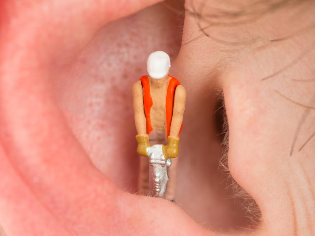 Een oor met een poppetje erin met een drilboor