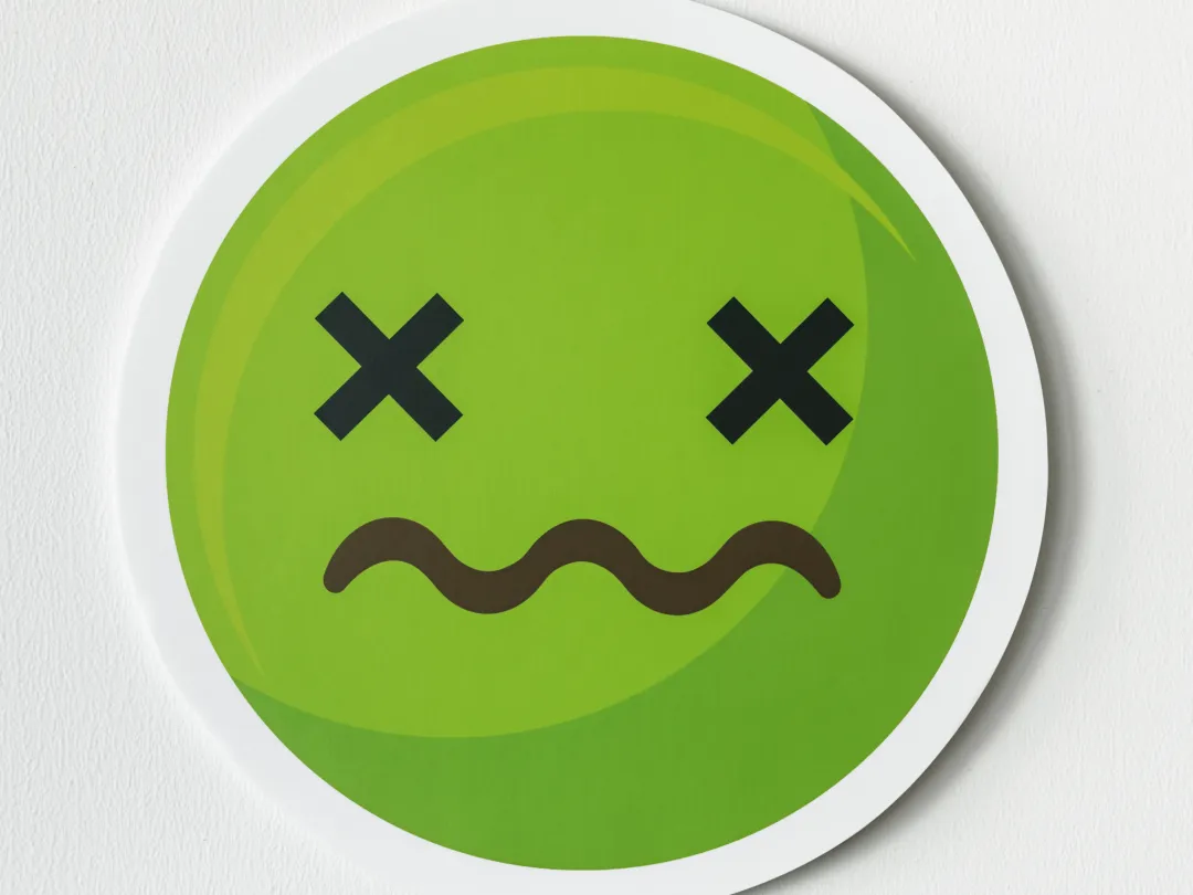 Een groene smiley met kruizen als ogen en een golvende mond