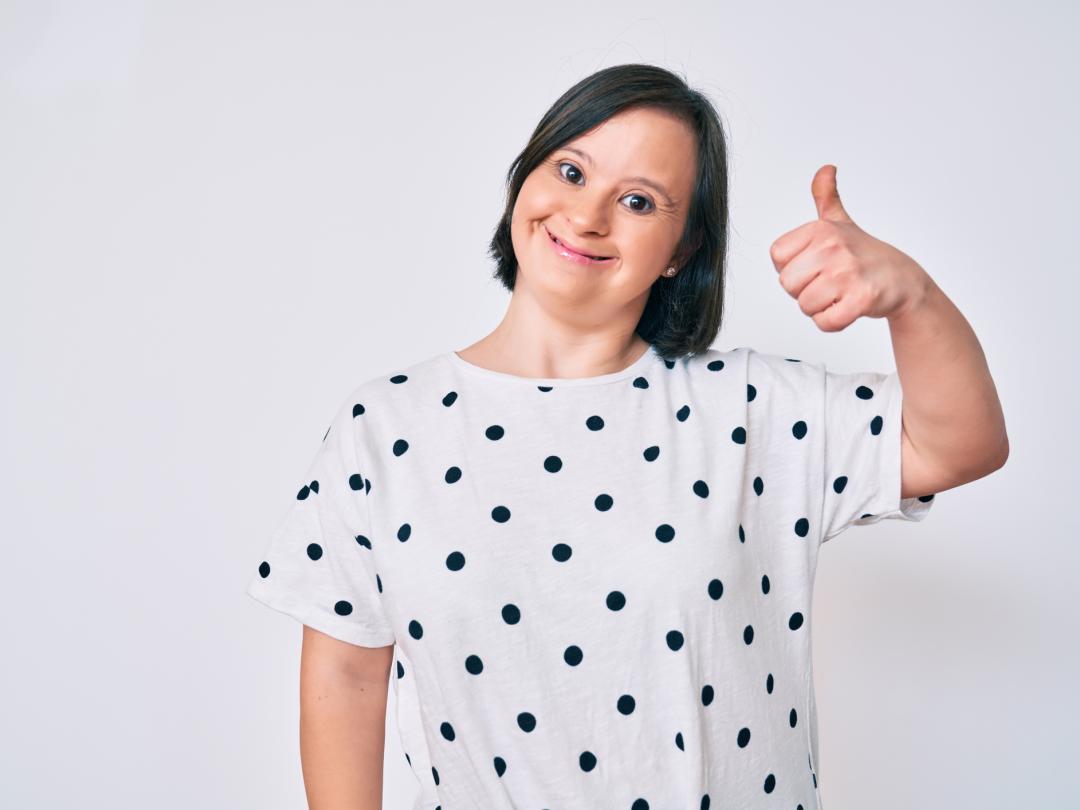 Vrouw met downsyndroom die duim omhoog houdt